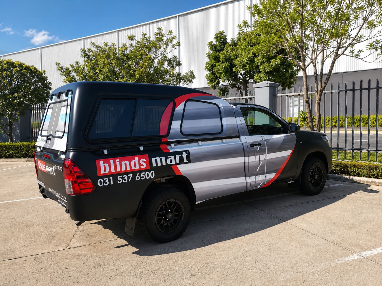 Toyota Hilux with a black and red Blinds Mart vehicle wrap